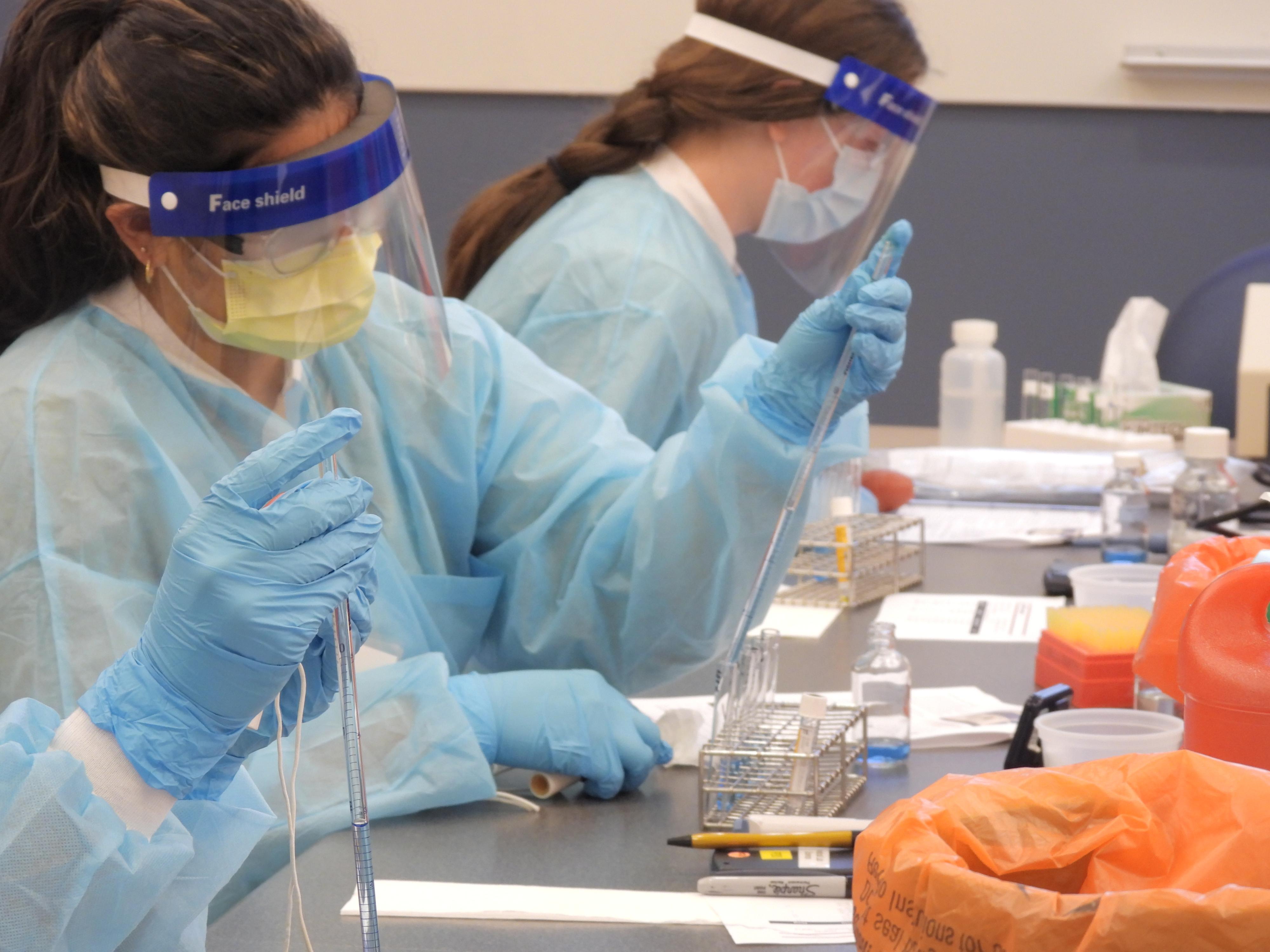 Summer immersion student performs an experiment while wearing PPE.