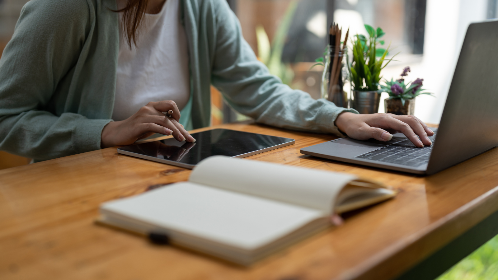 image of a person working at a table with a laptop and tablet