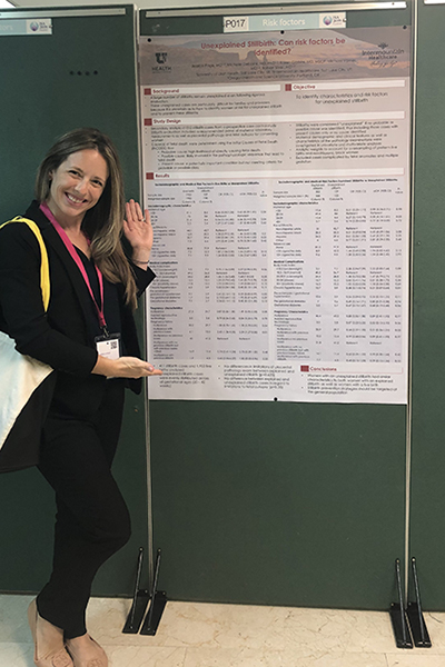 Dr. Jessica Page standing next to her poster at the ISA Conference.
