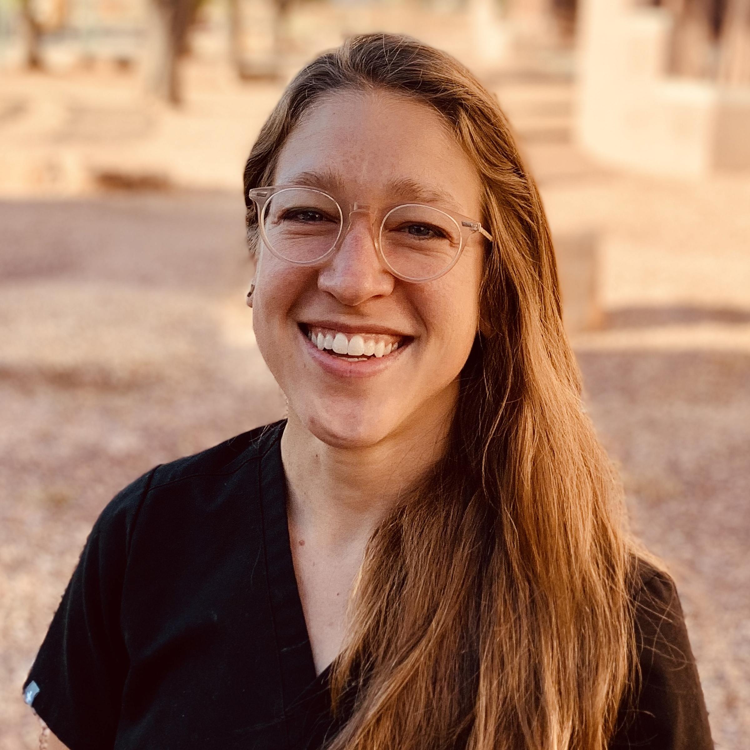 Dr. Kate Cohen smiling headshot with clear glasses and wearing a black top