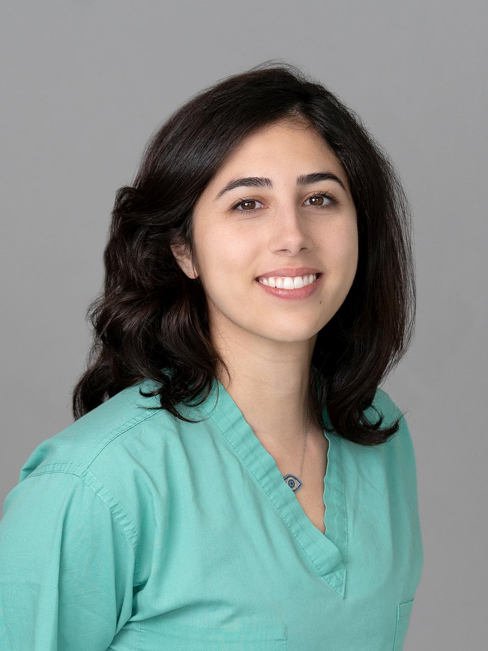 Photo of a woman, Dr. Hanna Fanous, with dark hair wearing green scrubs smiling at the camera.