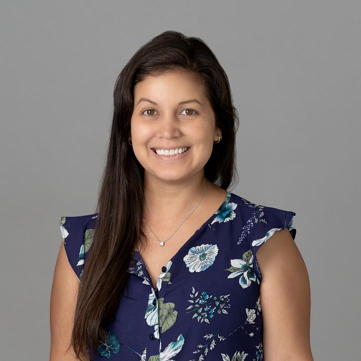 Photo of a woman, Dr. Diana Melo, with long dark hair wearing a floral shirt smiling at the camera.