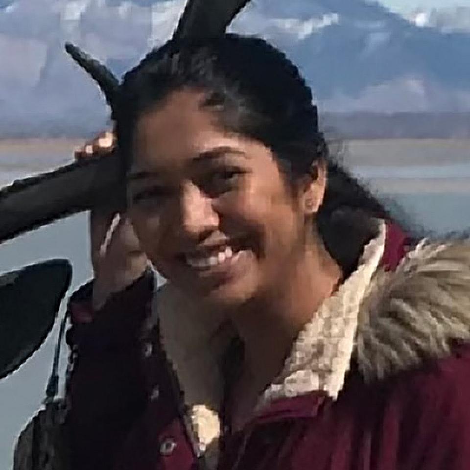 girl with dark hair in a ponytail posing in front of the lake