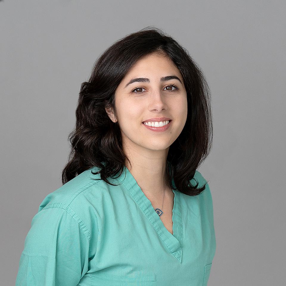 Photo of a woman, Dr. Hanna Fanous, with dark hair wearing green scrubs smiling at the camera.