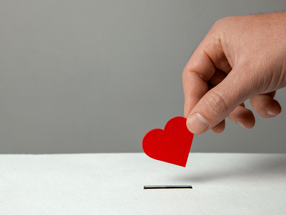 Heart-shaped card being placed into a donation box.