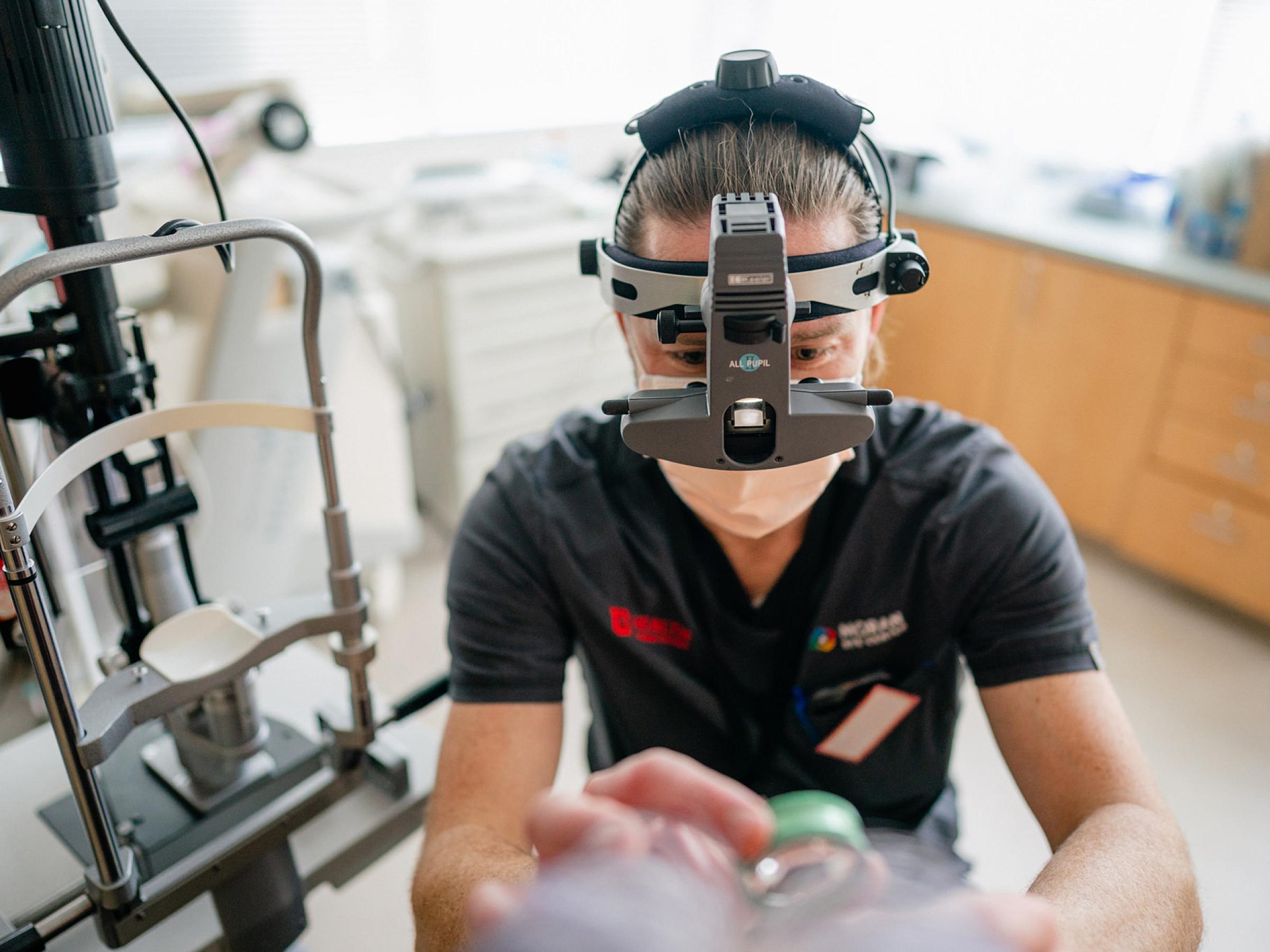 A resident performs an eye exam.