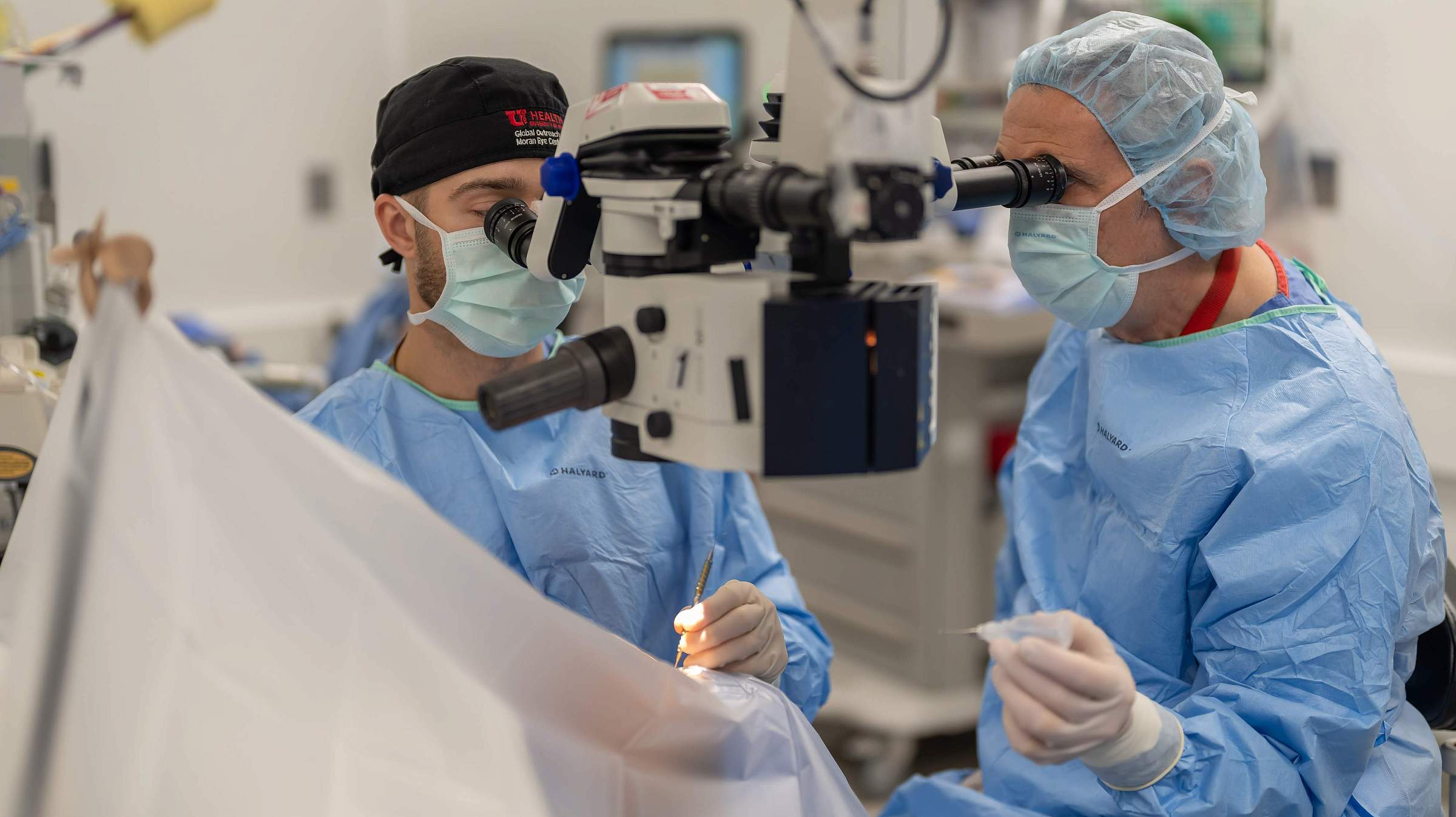 Nick Mamalis, MD, right, performs cataract surgery with a resident in 2024. 