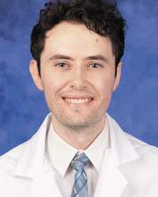 David Hallan wearing a white coat and tie