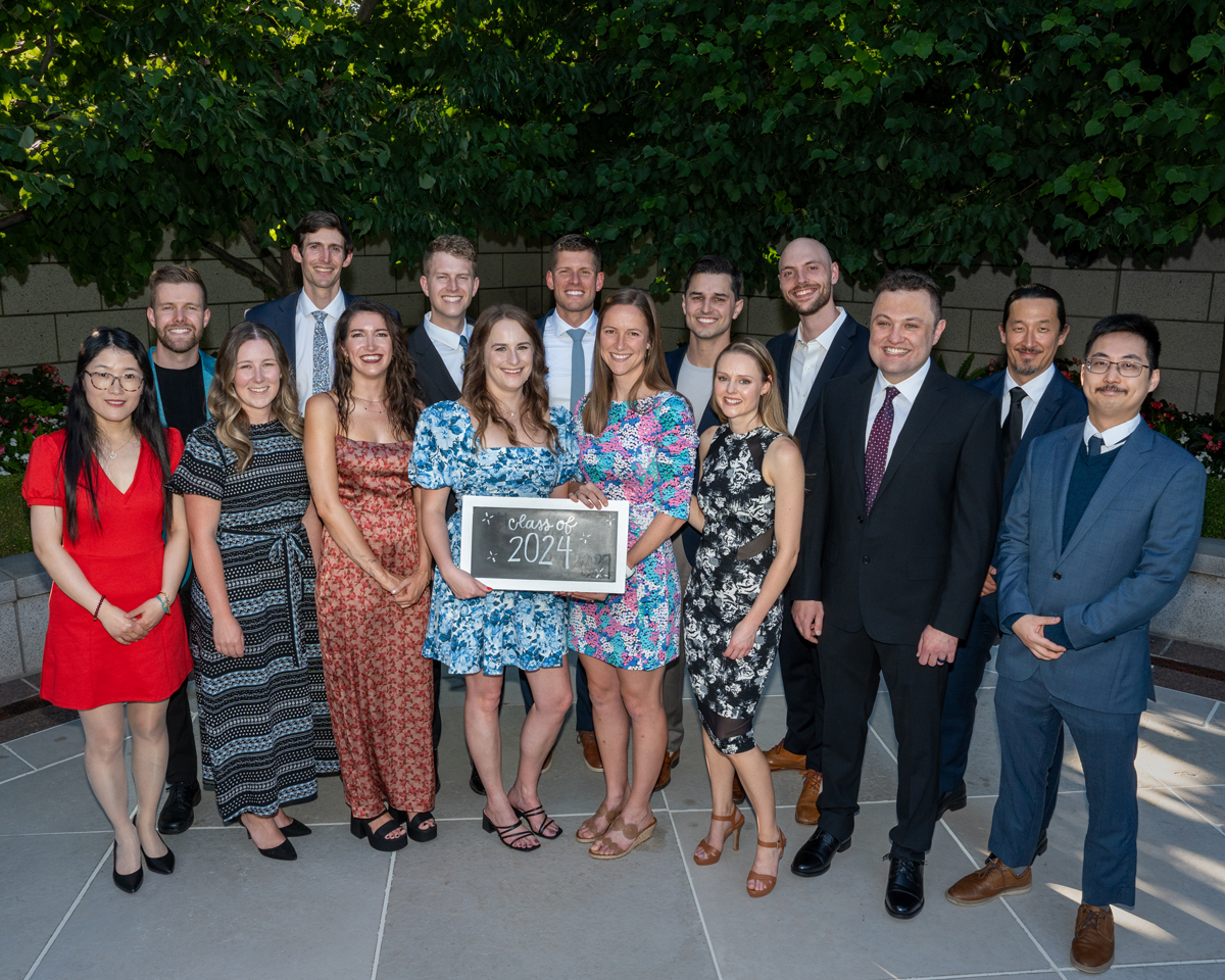 15 people smiling for a photo, holding a sign that says, "Class of 2024"