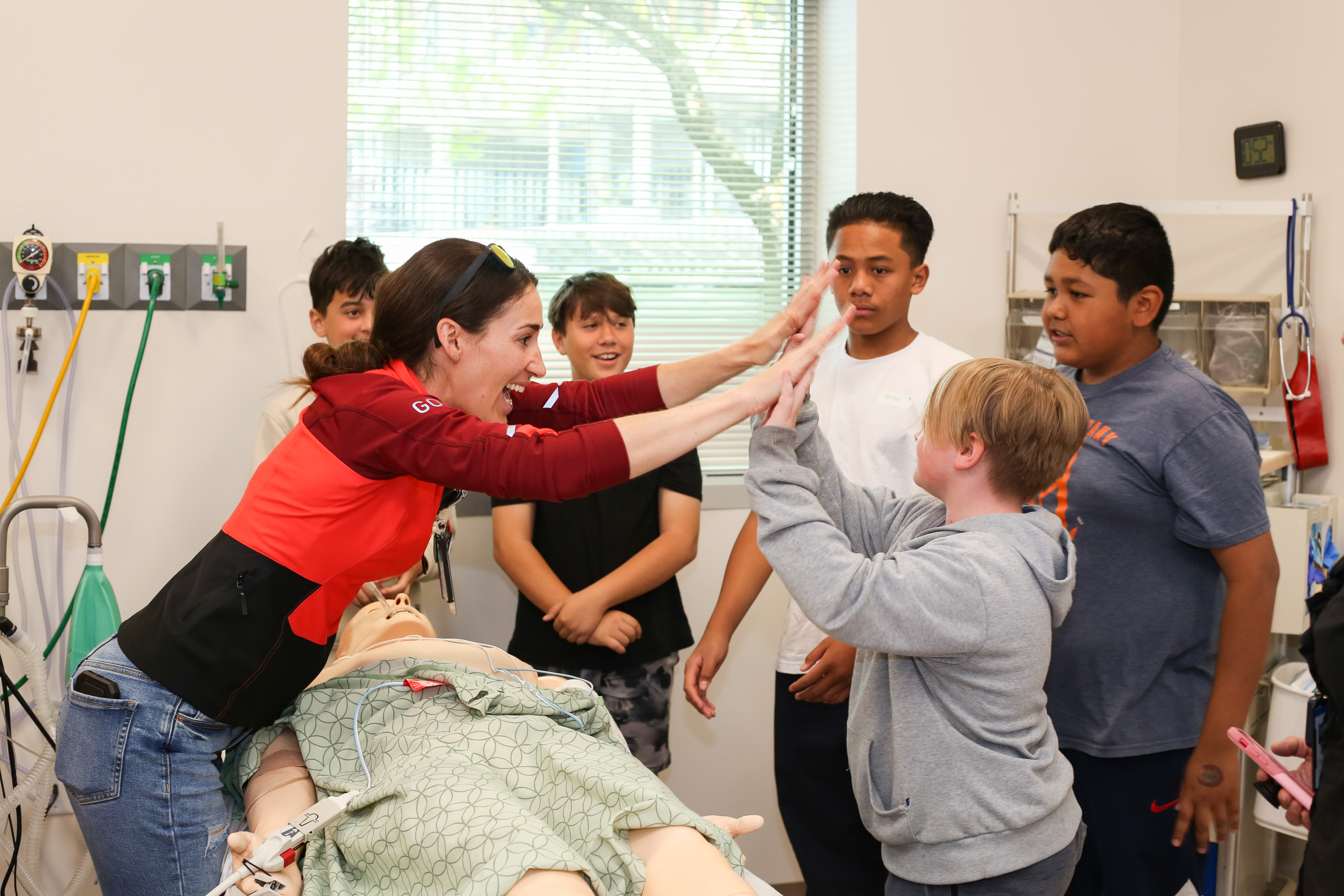 A doctor high-fiving a group of students in a simulation lab. 