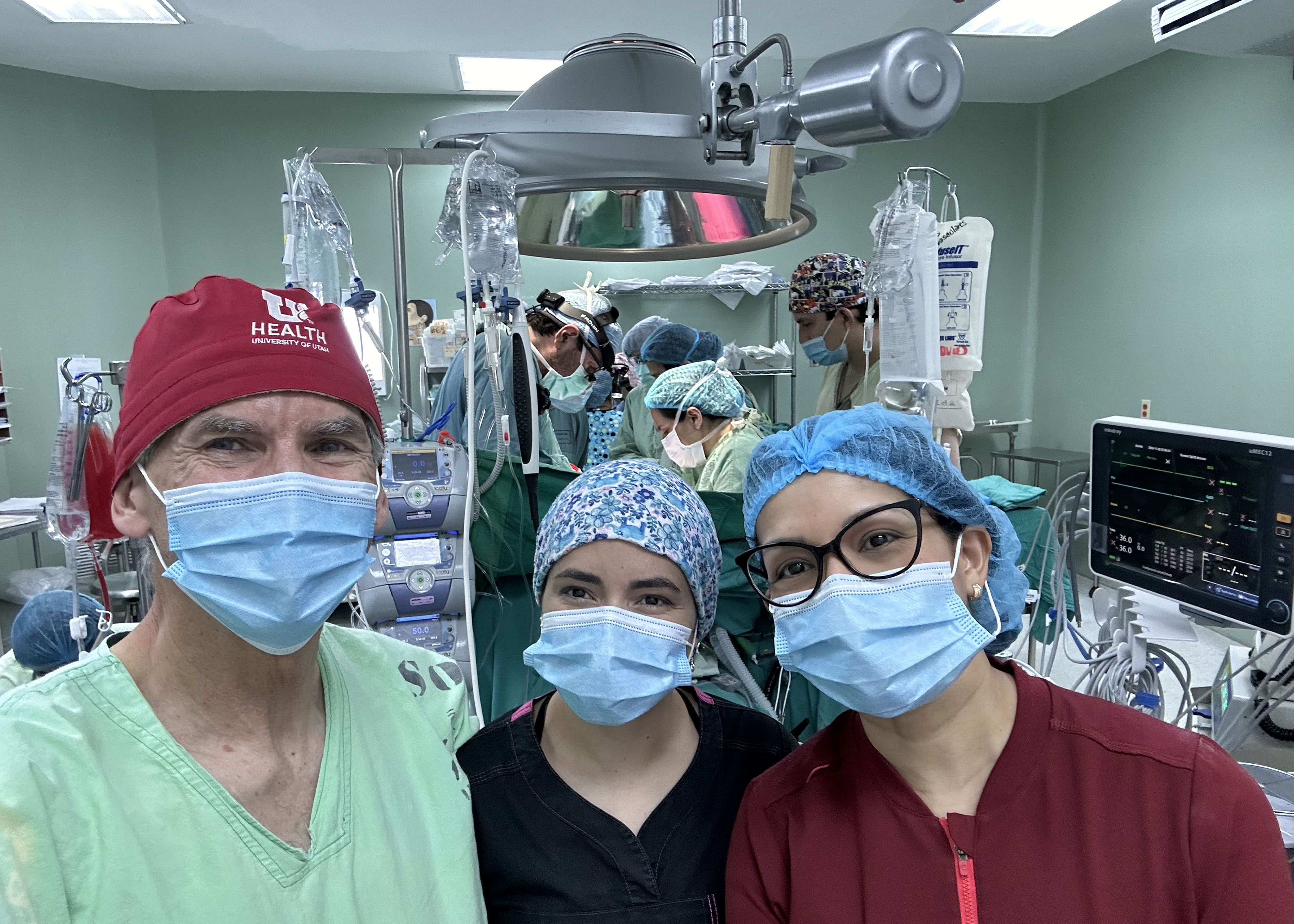 Dr. Bott and two other doctors in an operating room. All three wear surgical masks and are looking at the camera.