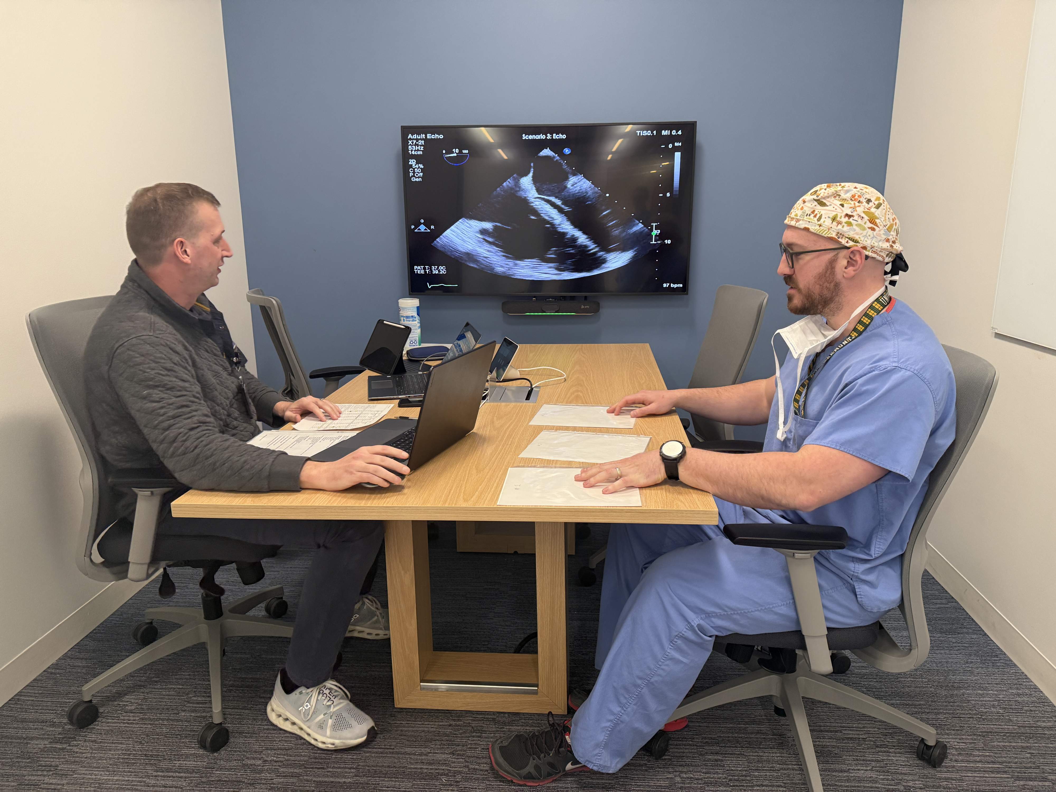 A resident interpreting an Echo on a large display for a faculty member.