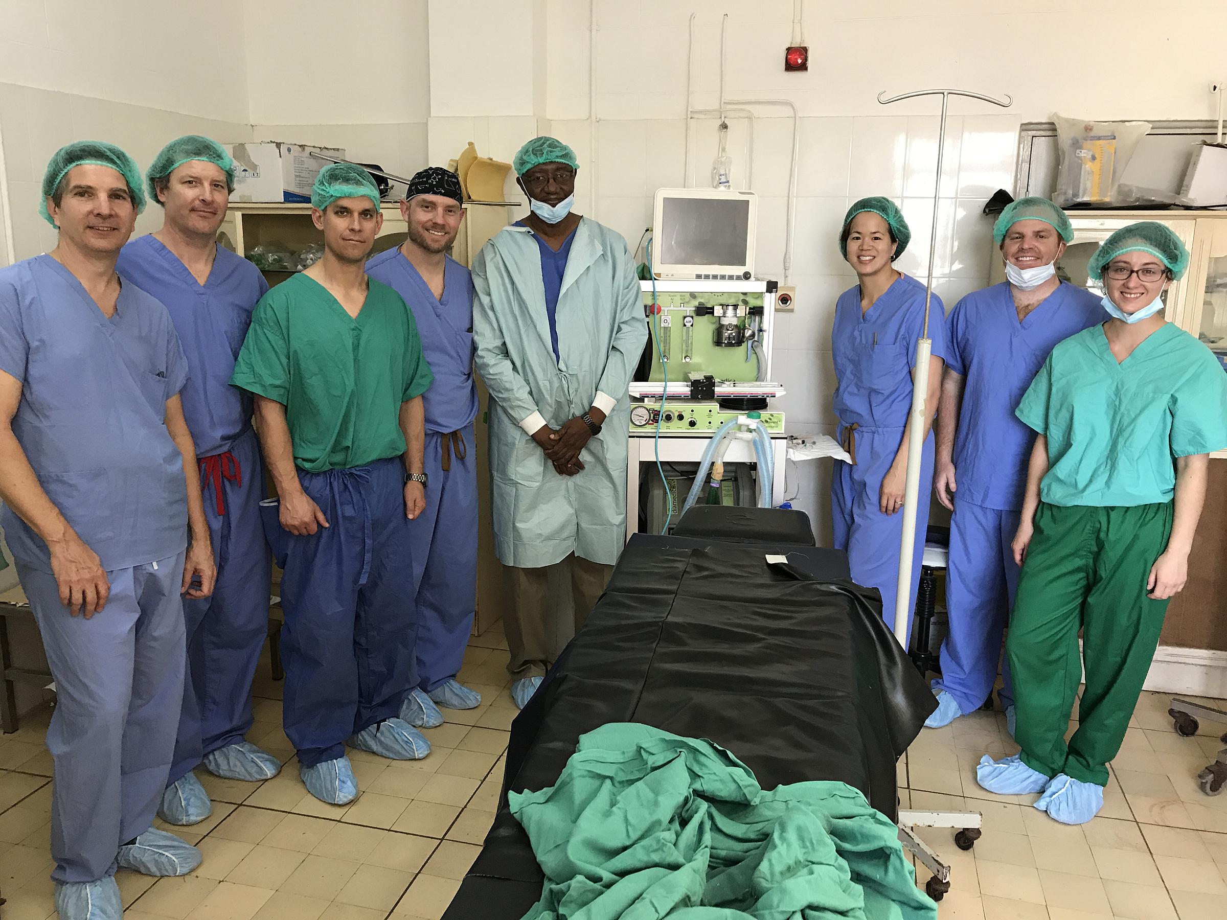 8 doctors standing together for a photo in an OR in The Gambia.