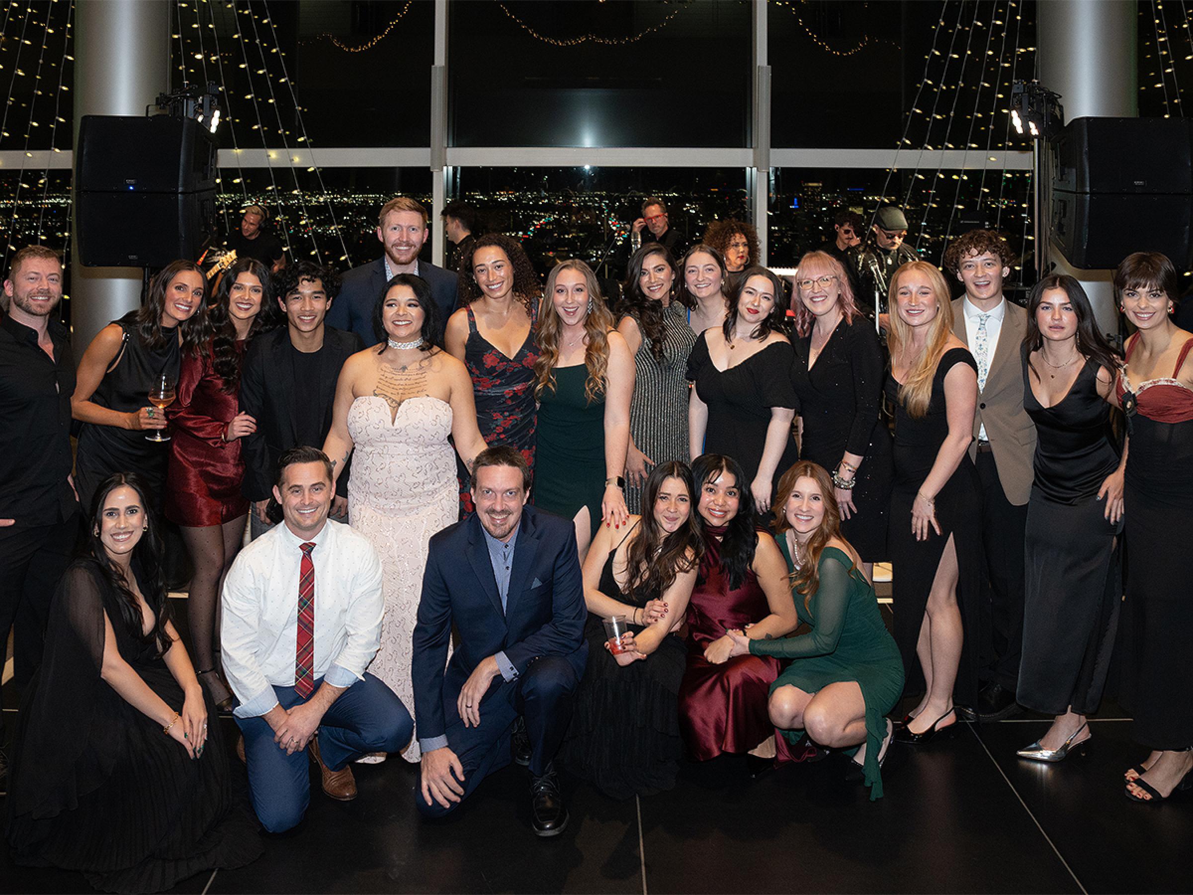A large group of 22 people smiling together for a photo on the dance floor. 