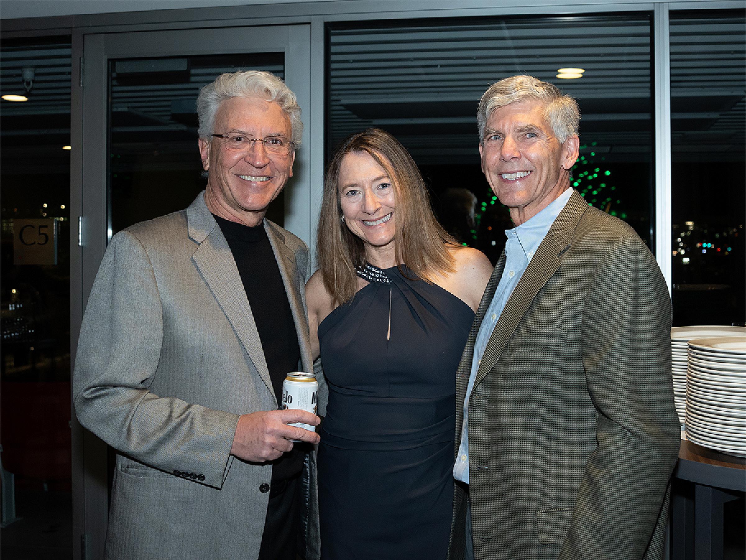 Three people smiling together for a photo at the holiday party. 