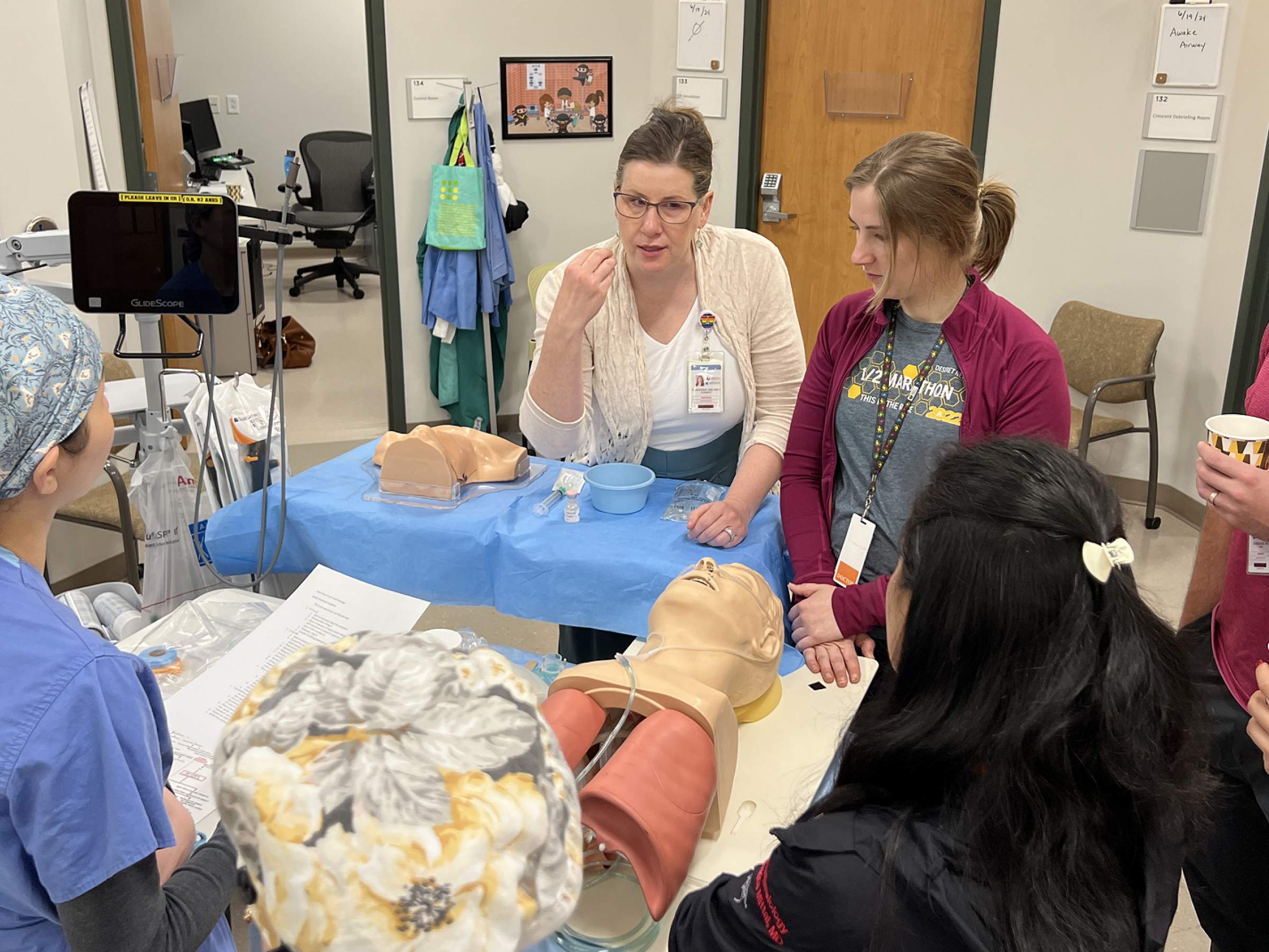 A faculty member instructing a group of 7 residents on airway management.