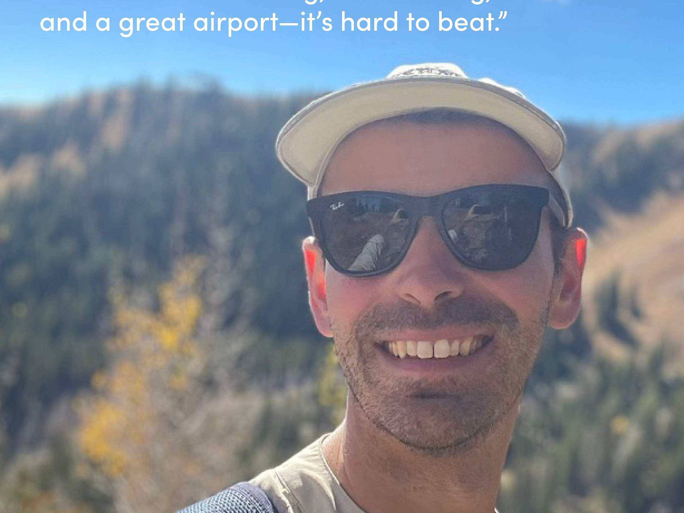 A selfie of Dr. Guay while taking a hike in the mountains. He wears a pair of sunglasses and a brimmed hat.