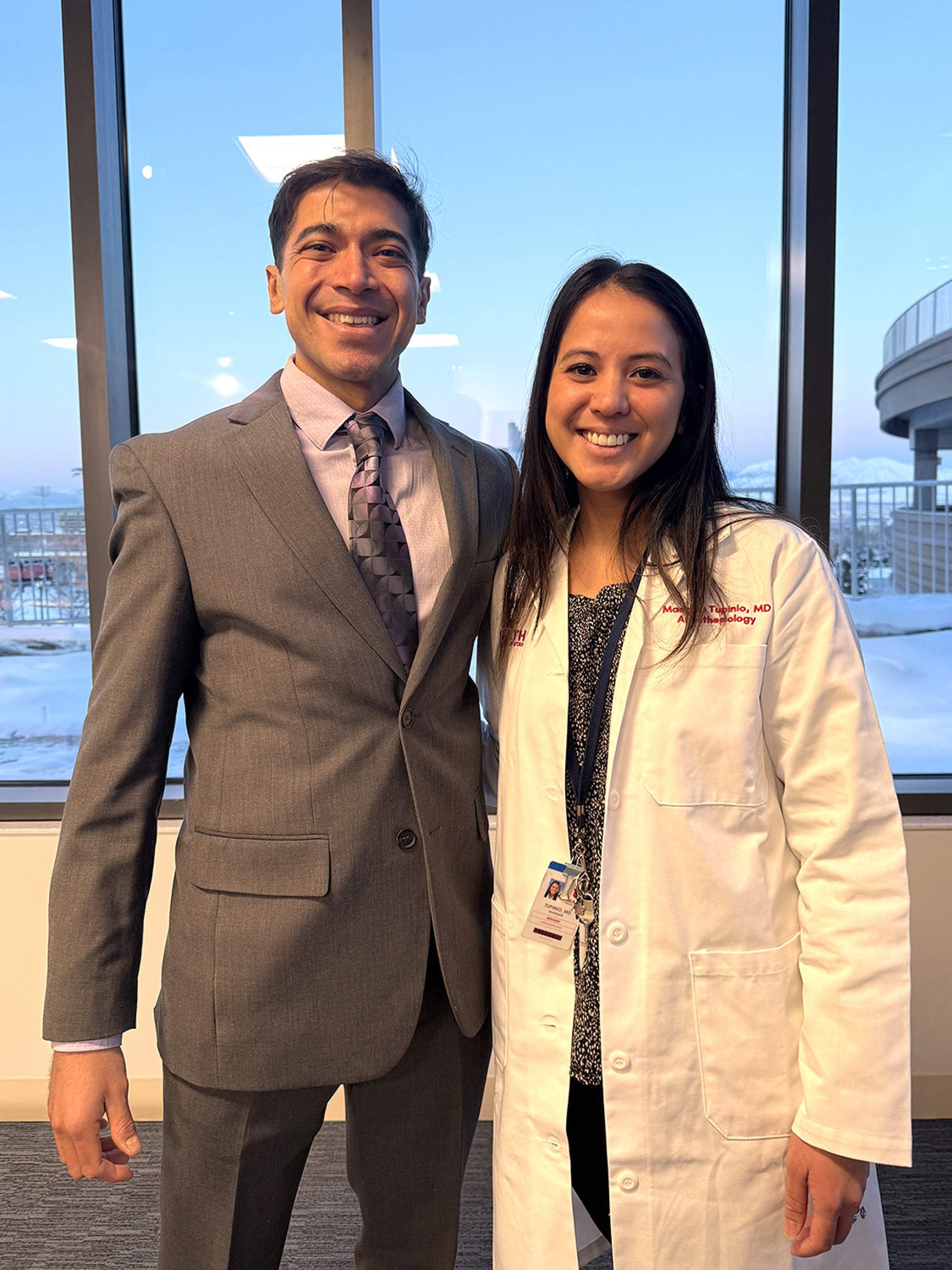 Dr. Juan Macias and Dr. Maegen Tupinio pose for a photo together at the HELIX building. They stand next to each other and smile at the camera.
