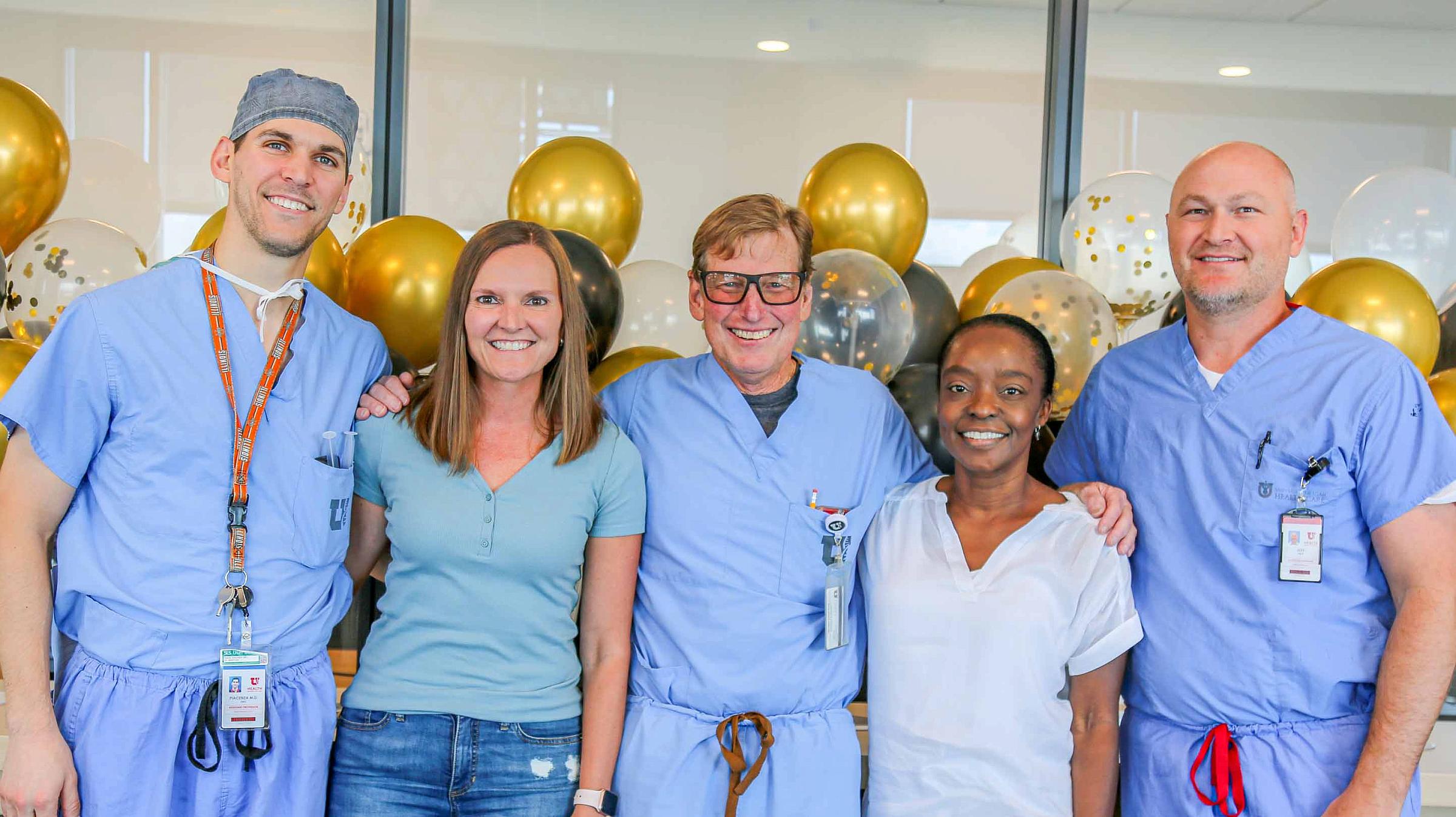 A group of people smiling together for a photo for a retirement party. Gold and black balloons are behind them.