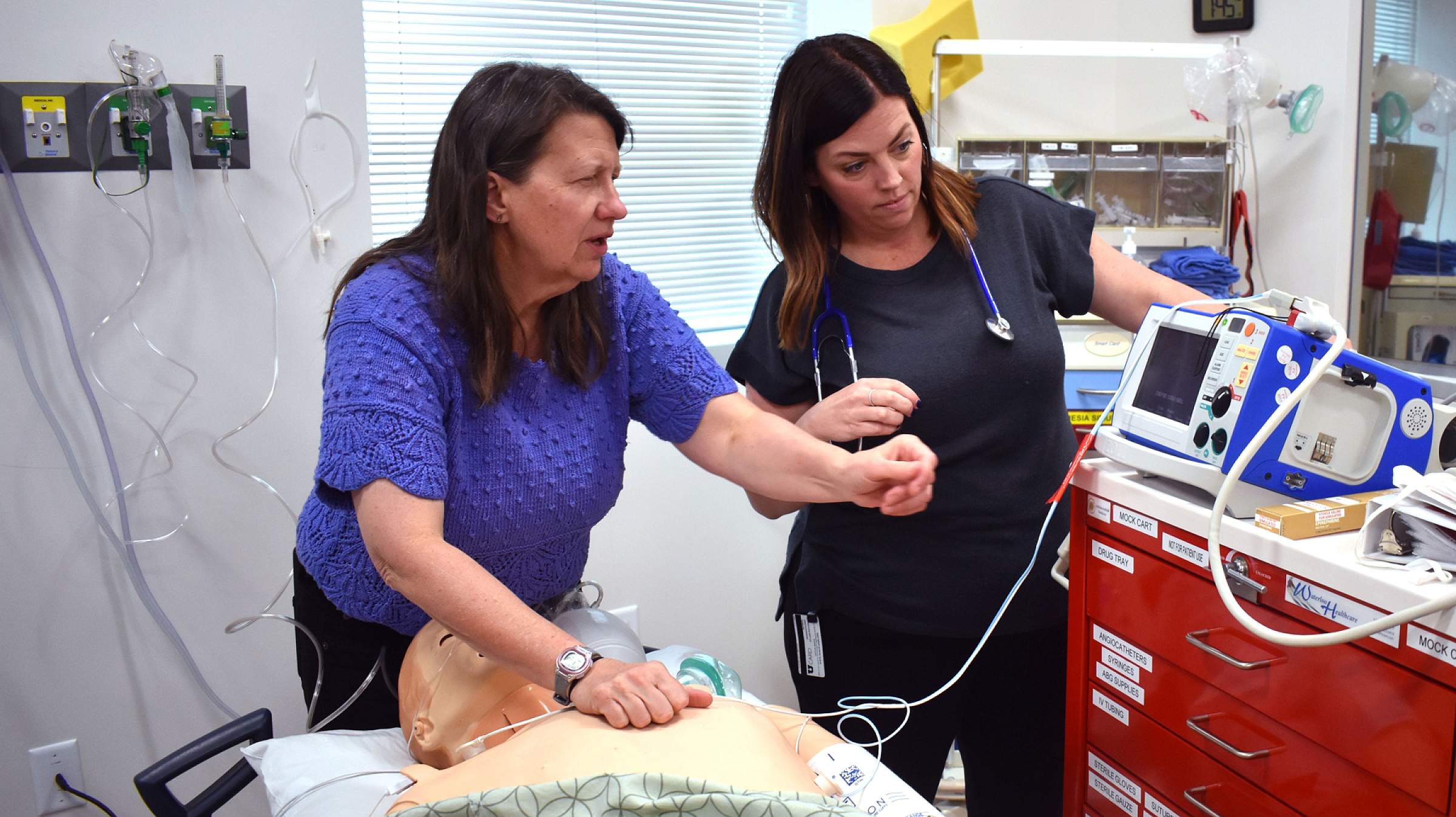 A faculty member instructing someone on how to do advanced cardiac life support.