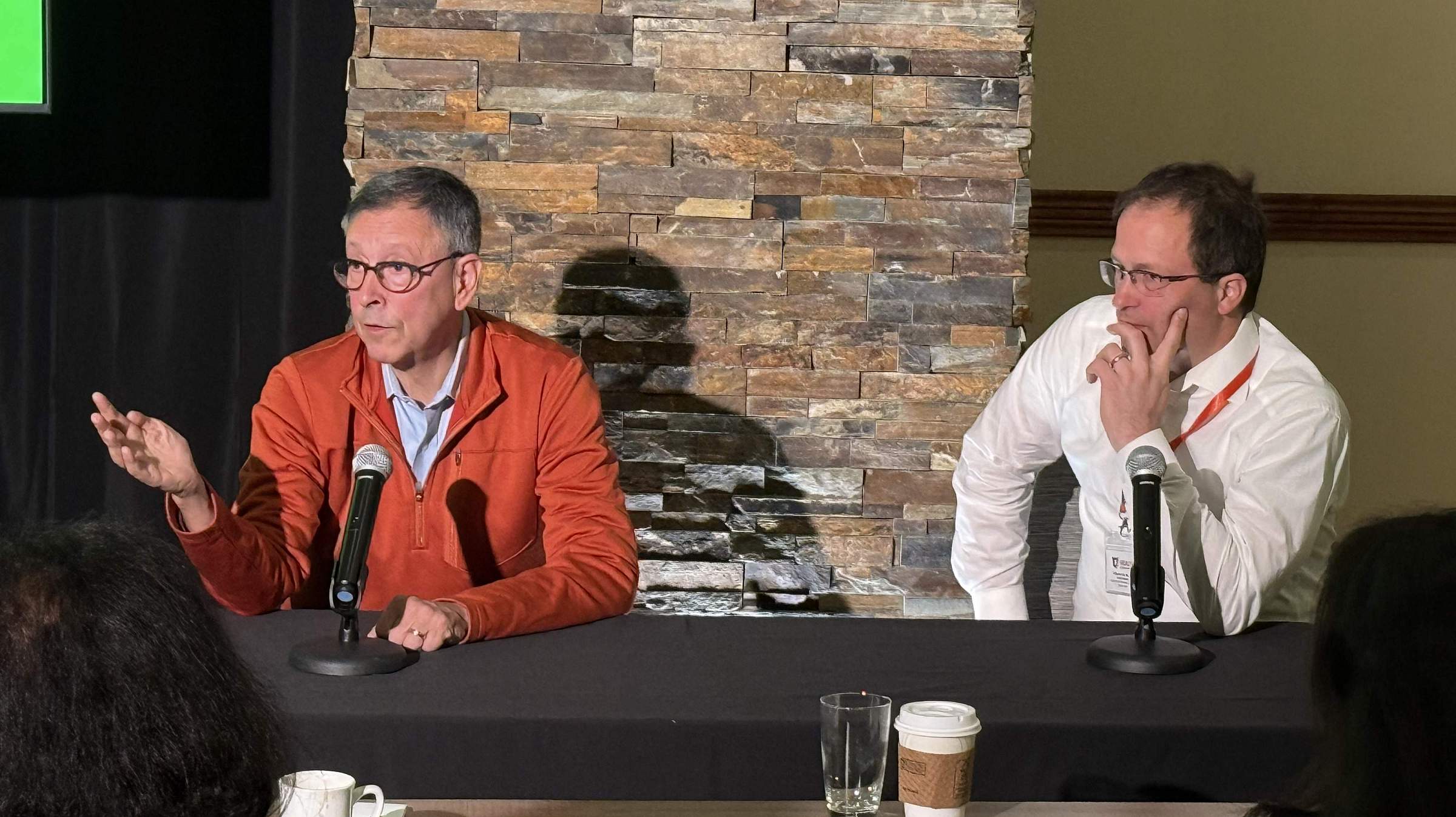 Drs Evan Kharasch and Philipp Lirk answer questions from attendees. Dr Kharsasch sits on the left and wears an orange sweater over a light blue button-down shirt. Dr. Lirk sits on the right with a white button-down shirt.