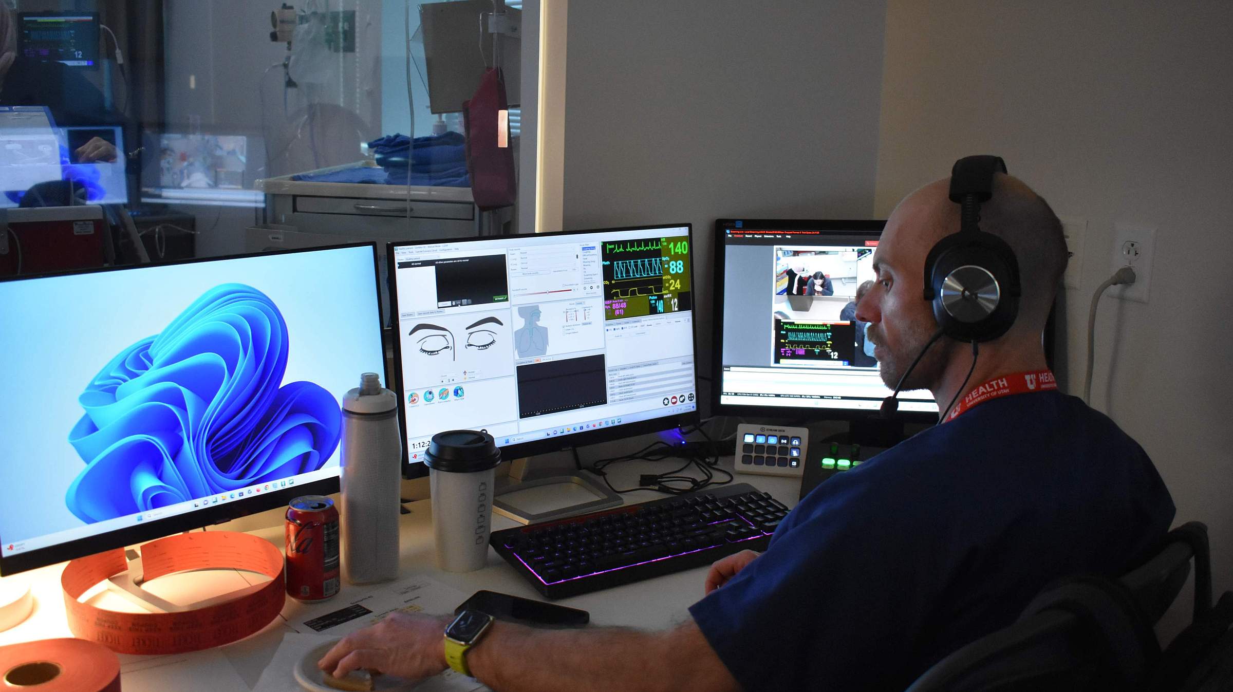 An individual in front of three computer monitors, wearing a headset.