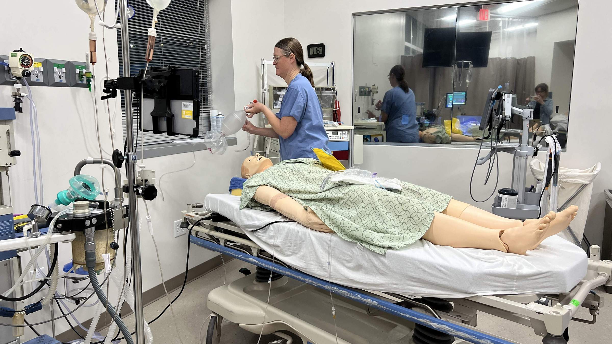 A doctor in a simulated operating room with a simulated patient and medical equipment.