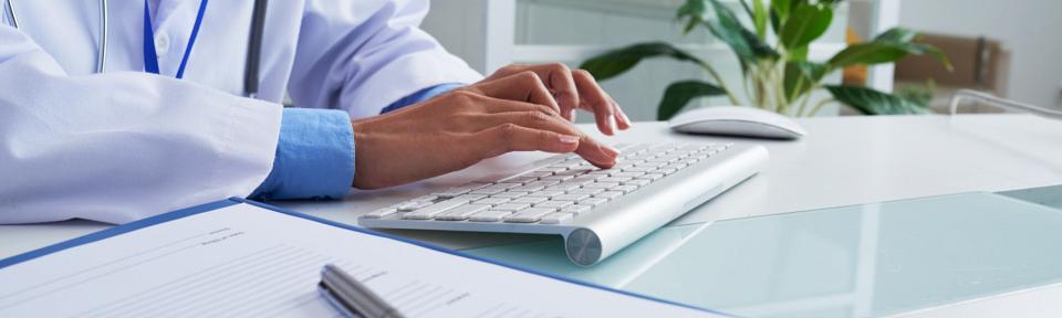 Hands of unrecognizable female doctor typing on keyboard in office